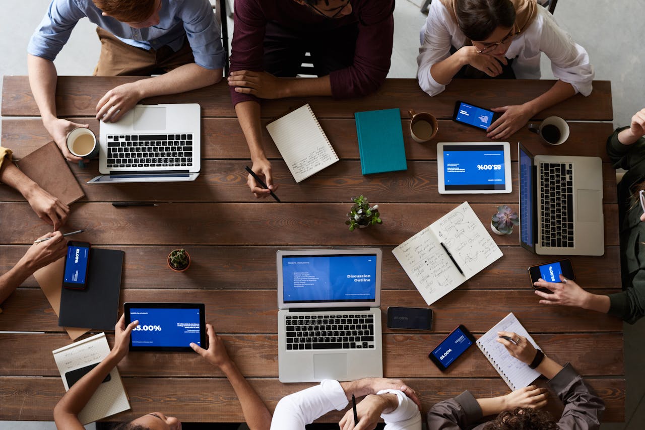 services-02 Overhead view of a diverse team in a business meeting using laptops and tablets.