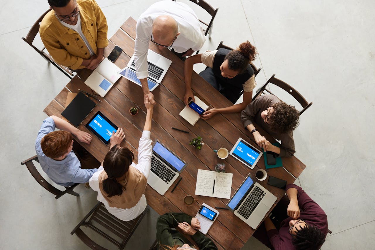 services-03 Top view of a diverse team collaborating in an office setting with laptops and tablets, promoting cooperation.